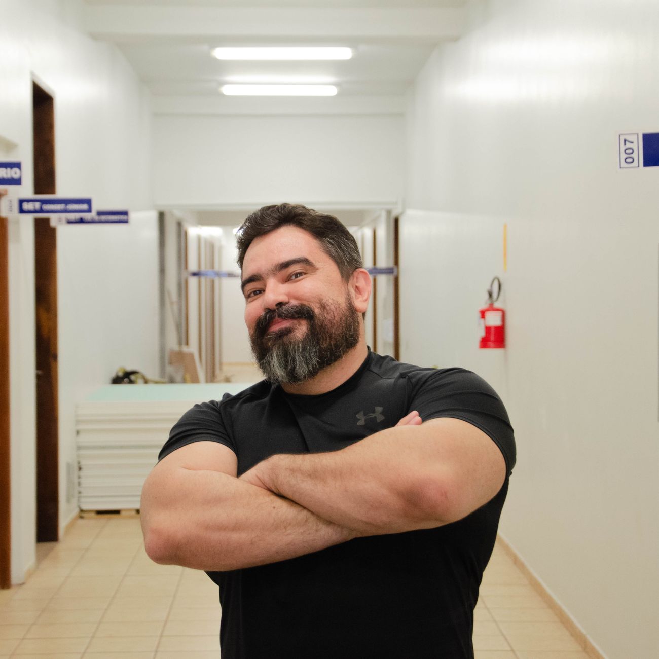 portrait of spatial designer smiling in front of architectural floor plan with physical model on table